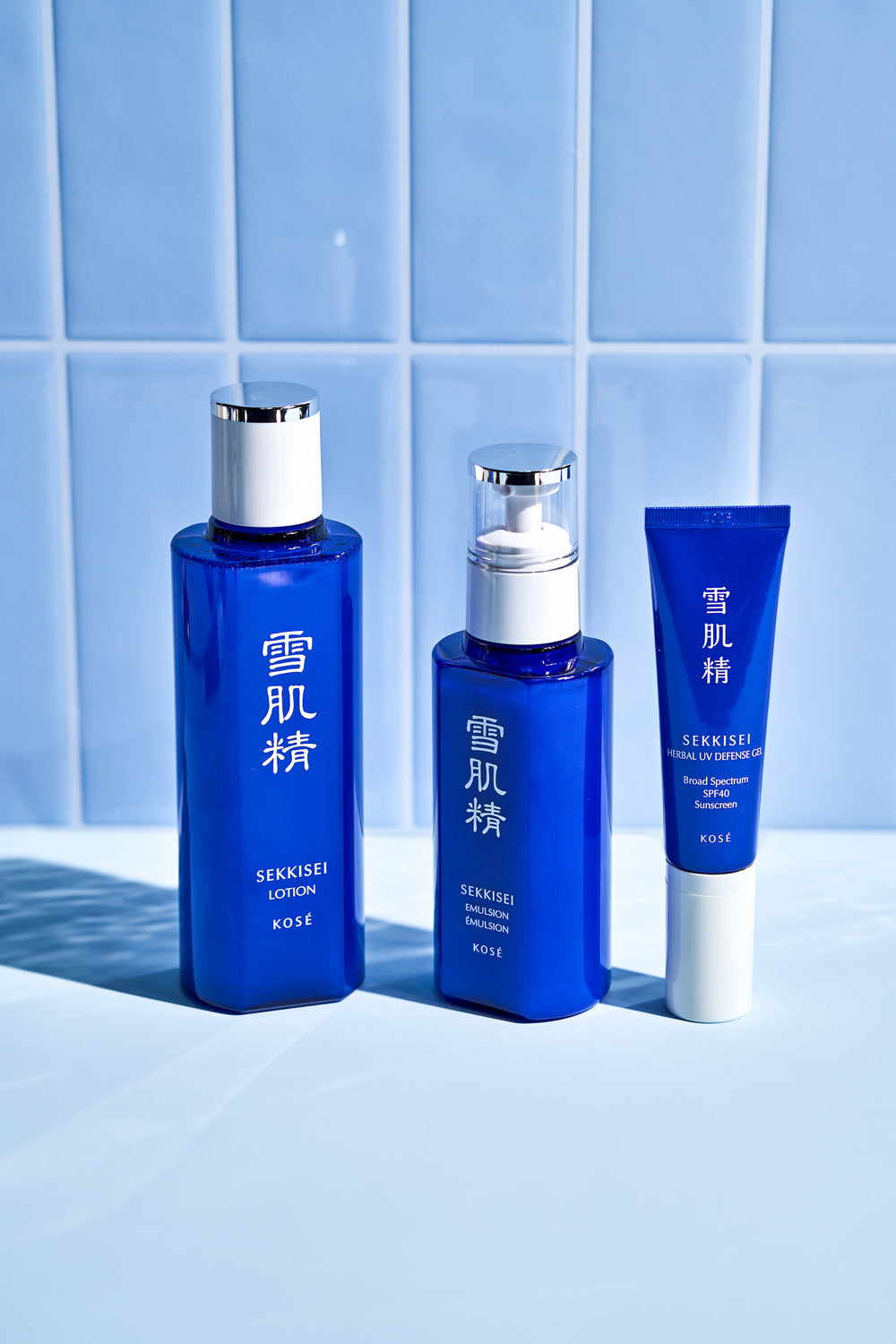 SEKKISEI Lotion, SEKKISEI Emulsion, and SEKKISEI Herbal UV Defense Gel on a light blue tiled background