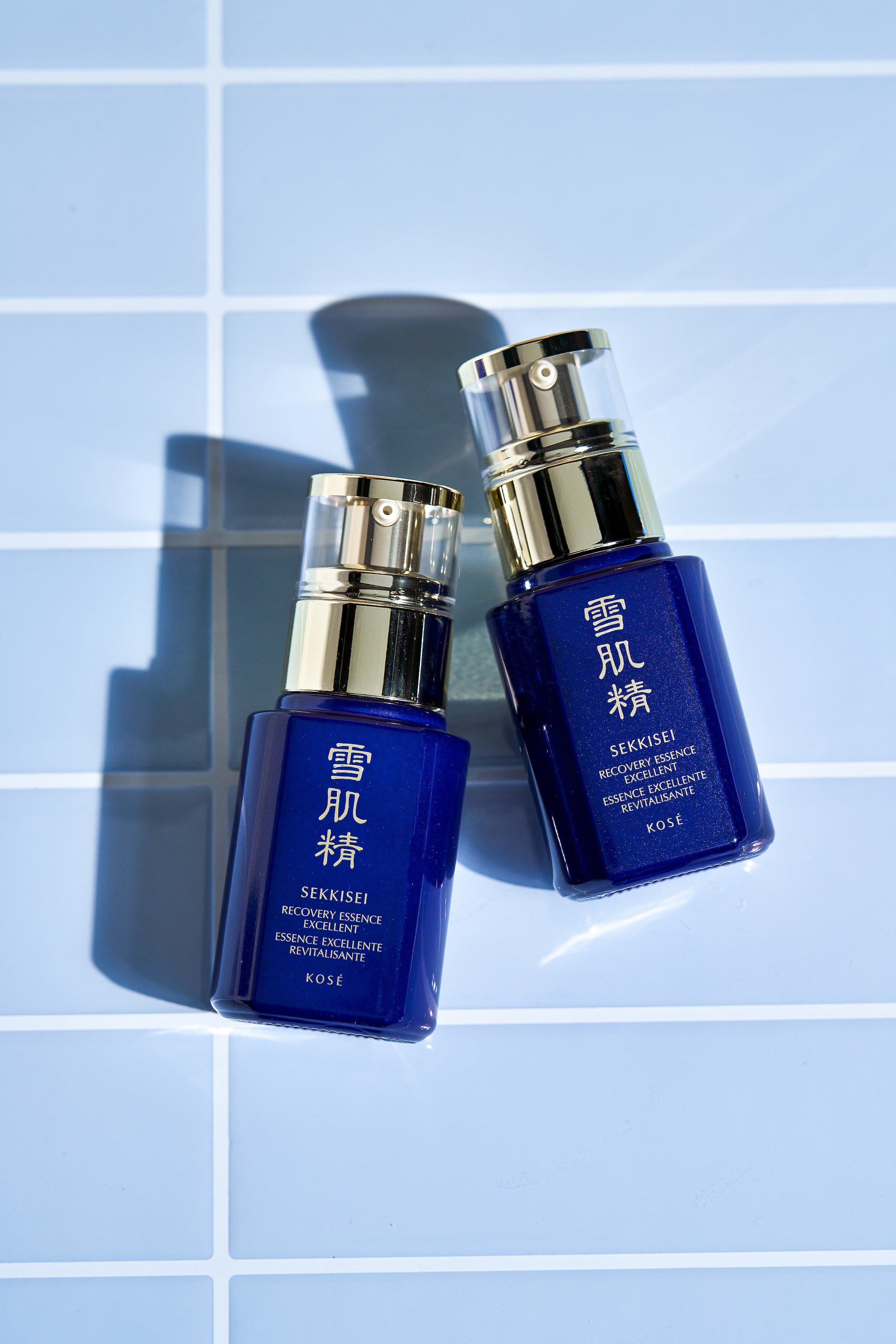SEKKISEI Recovery Essence Excellent bottles on a light blue tiled background