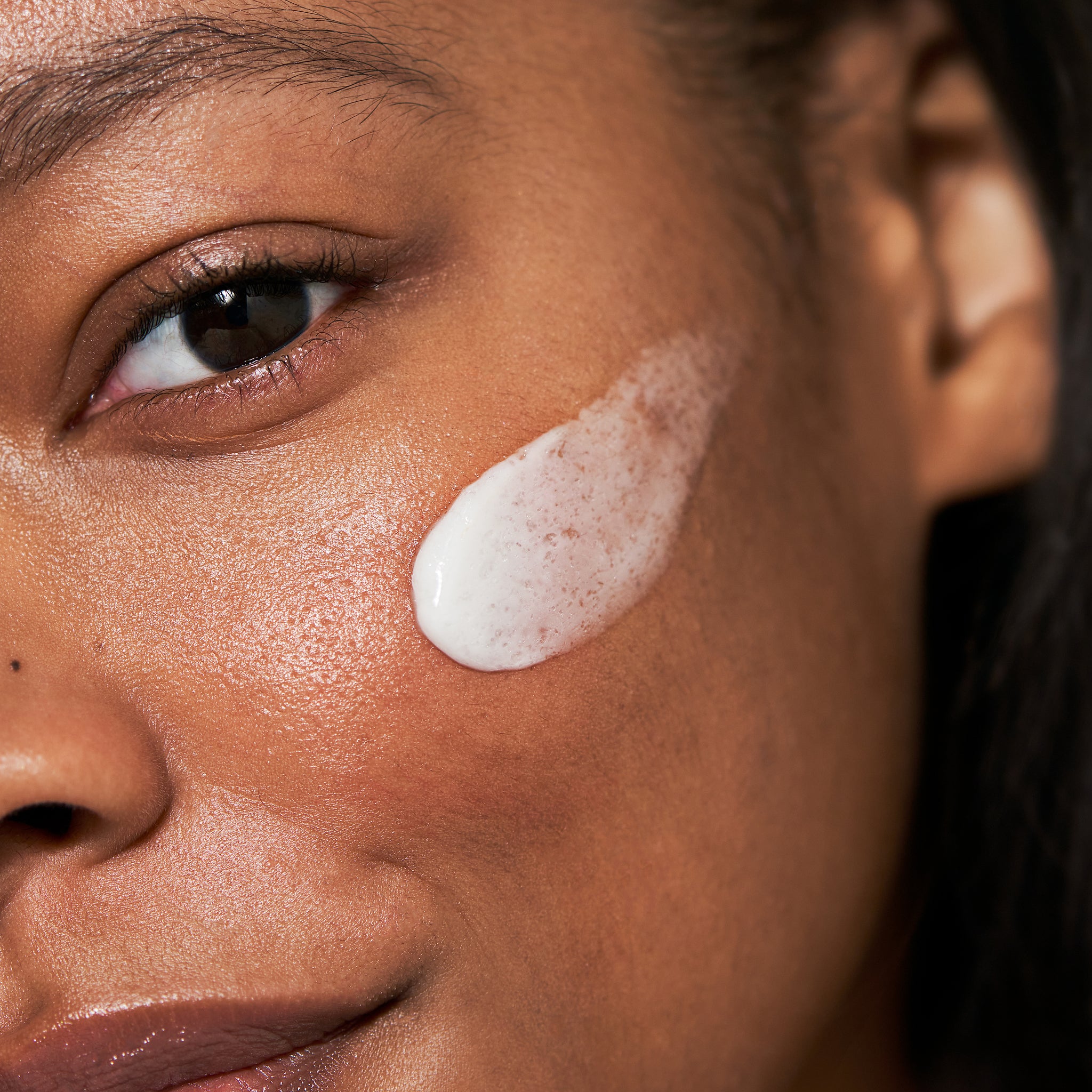 Close-up of a woman's face with a SEKKISEI cream excellent applied to her cheek.