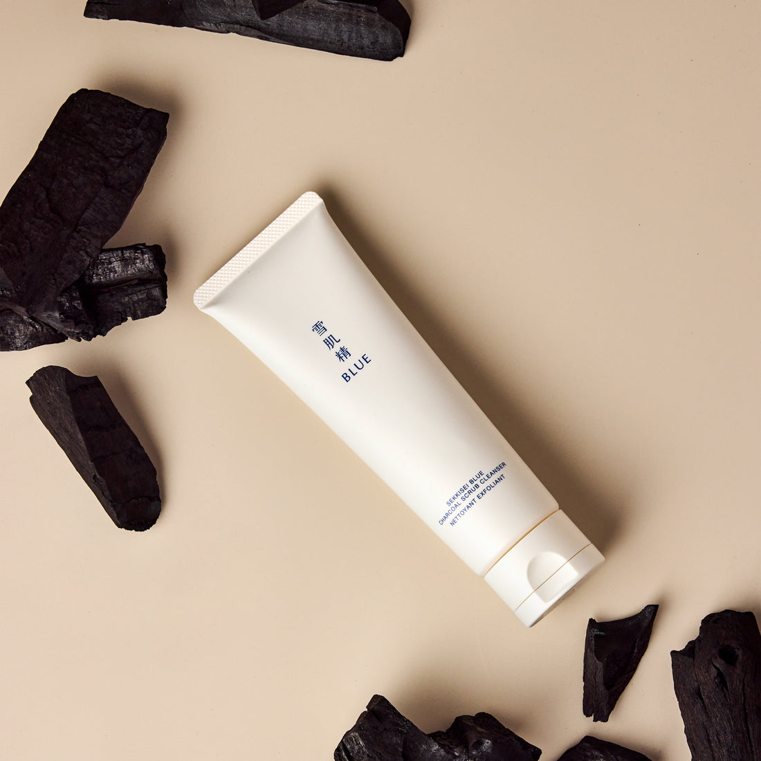 Blue Charcoal Scrub Cleanser surrounded by charcoal pieces