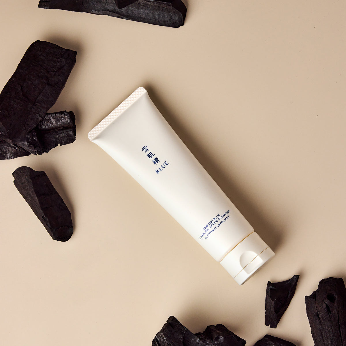Blue Charcoal Scrub Cleanser surrounded by charcoal pieces