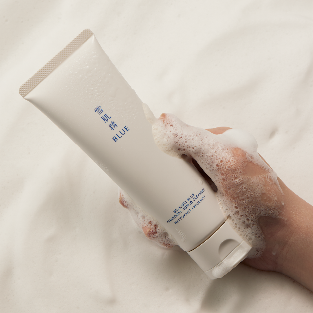 A hand covered in lathered foam holding Blue Charcoal Scrub Cleanser