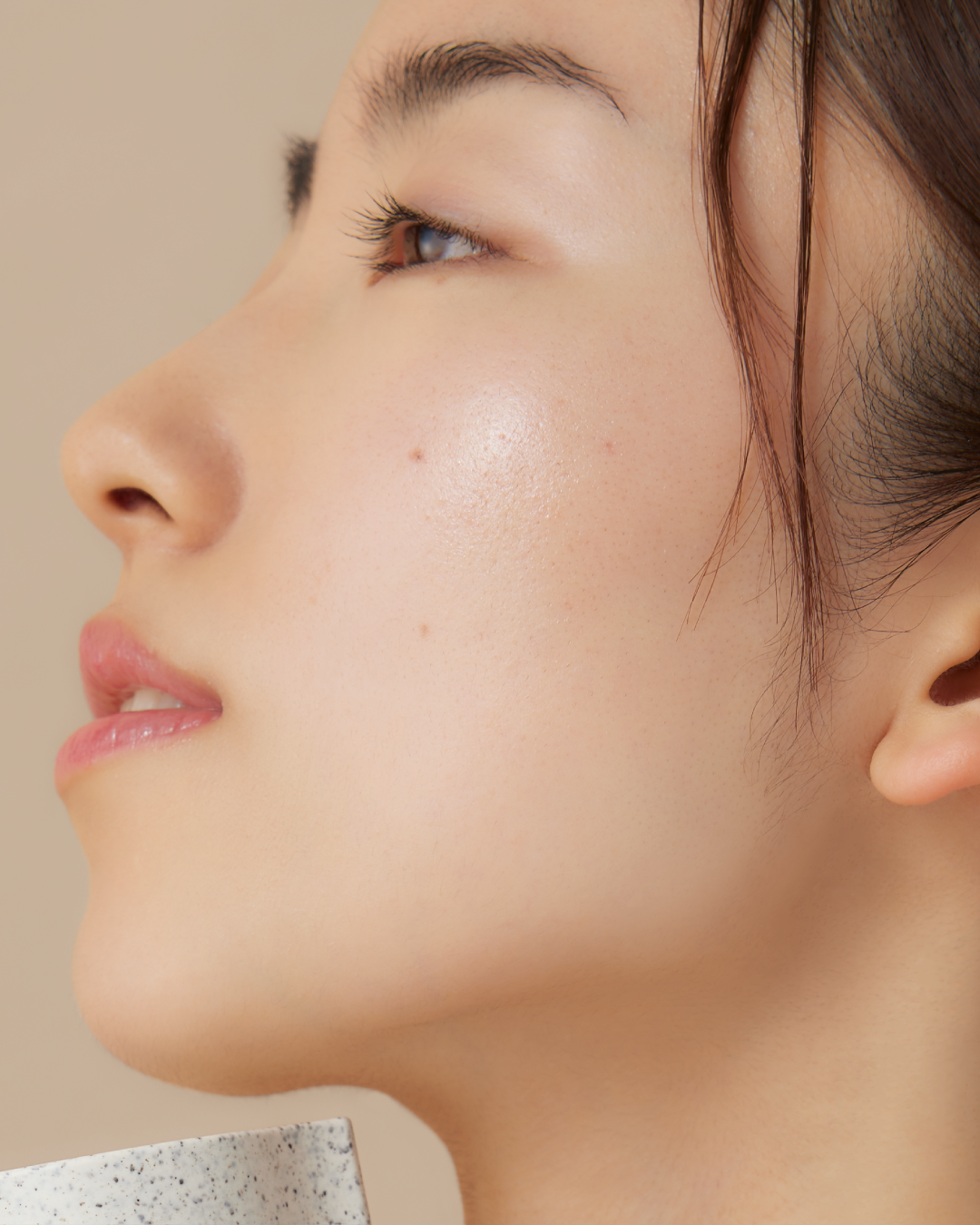 Close-up side profile of a woman's face showing a clear, glowing complexion
