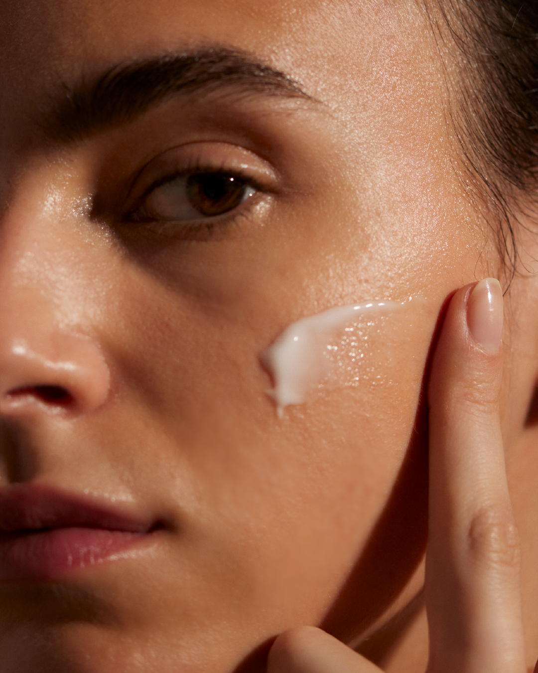 Close-up of a woman's face with Blue Smooth Hydrating Cream on her cheek
